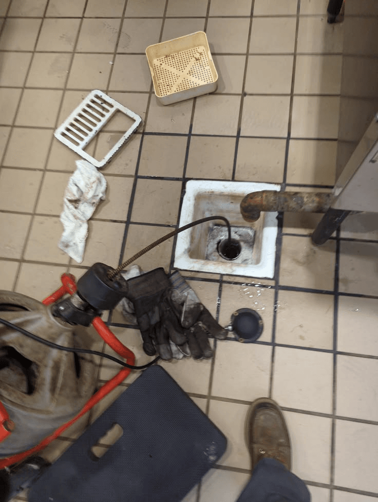 Drain-cleaning tools arranged around an open floor drain